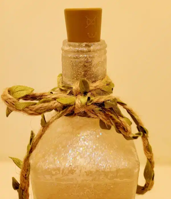 square gin bottle with jute twine around the neck. Green leaves on the twine.