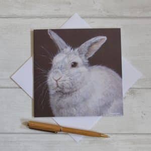 A rabbit art card. A white rabbit on a dark brown background. Square, blank inside with envelope.