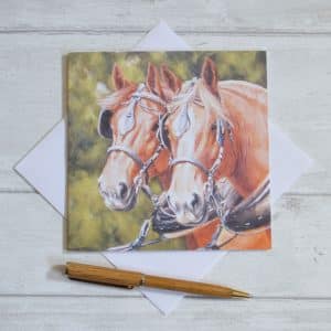 A pair of Suffolk Punch horses in working harness with green foliage behind and envelope.